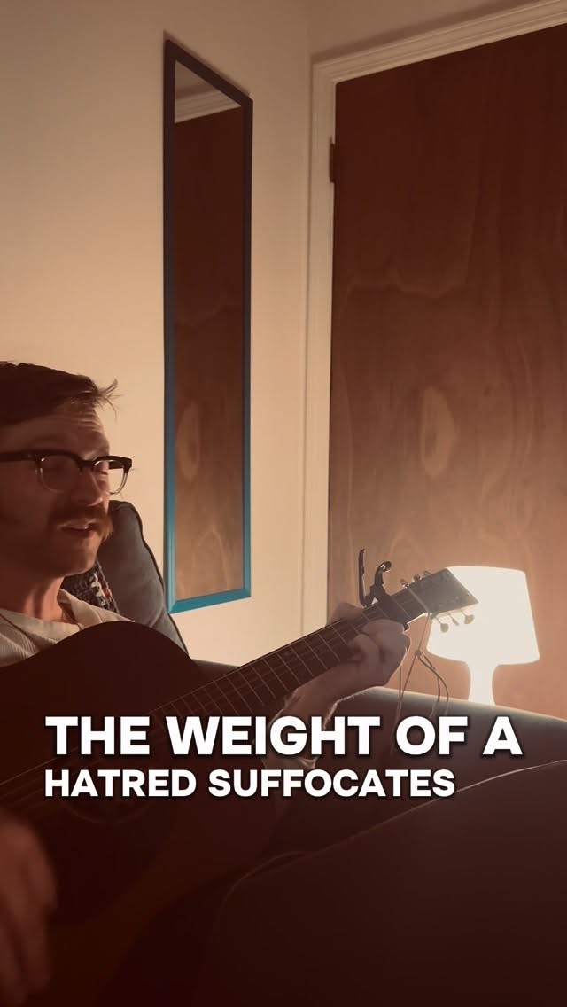 Clayton playing guitar in a warm room